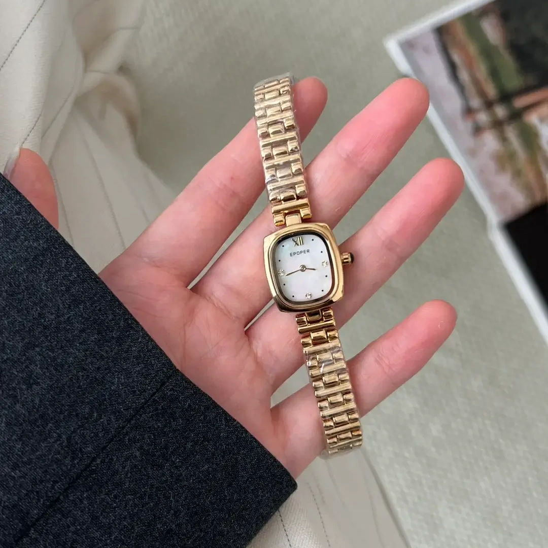 a hand holdChic Style Brown/White Oval Stainless Steel Bracelet Watching a gold watch