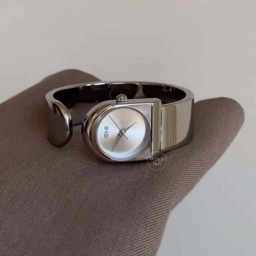 This stunning ladies' watch features a sleek silver-tone arched case paired with a clean, minimalist silver dial. Designed with a high-polish silver bangle band, it offers a perfect balance of modern elegance and chic style. Designed for women who love trendy, contemporary accessories, this versatile everyday watch adds a cool, polished touch to any outfit. It serves as an eye-catching bracelet watch for both daily wear and special occasions.