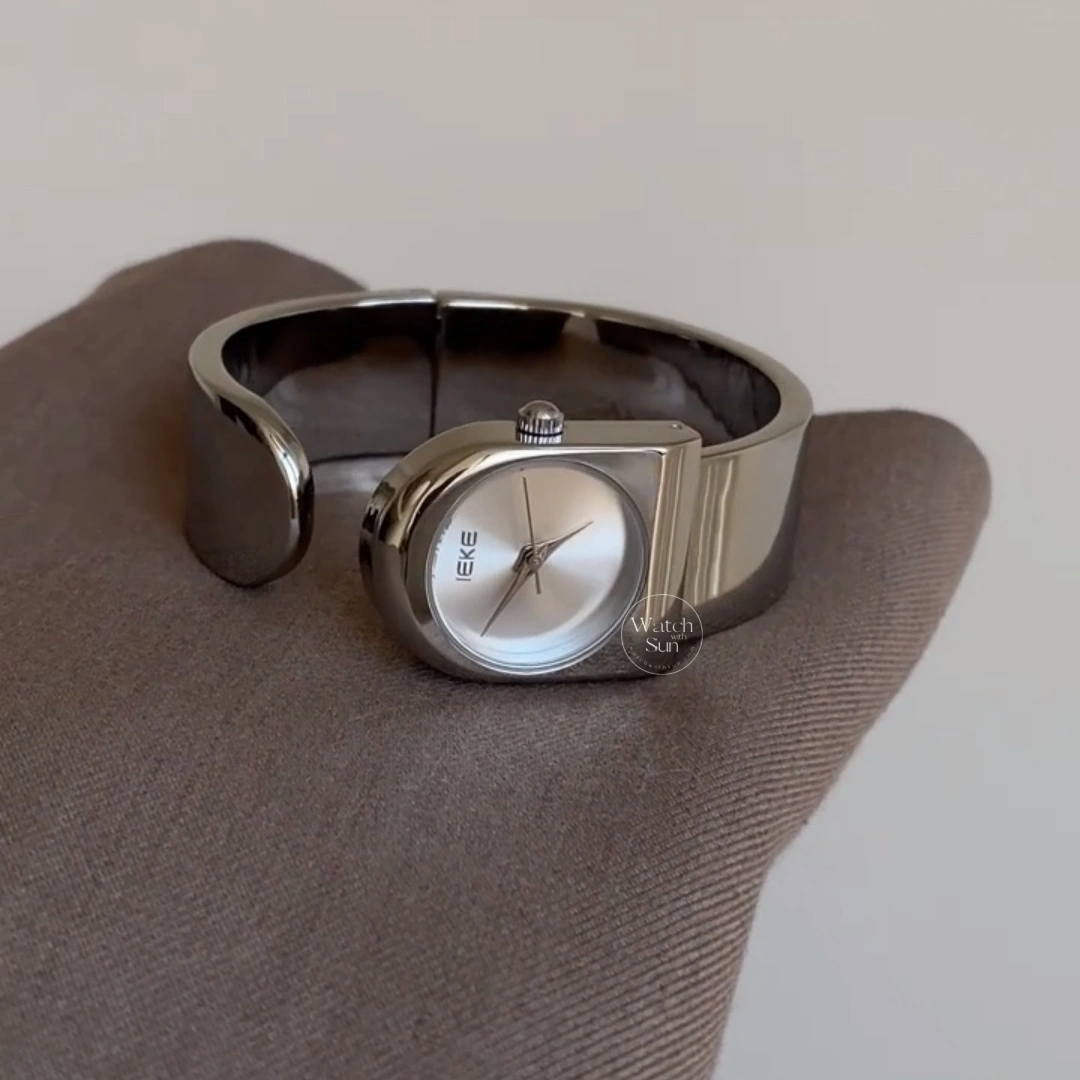 This stunning ladies' watch features a sleek silver-tone arched case paired with a clean, minimalist silver dial. Designed with a high-polish silver bangle band, it offers a perfect balance of modern elegance and chic style. Designed for women who love trendy, contemporary accessories, this versatile everyday watch adds a cool, polished touch to any outfit. It serves as an eye-catching bracelet watch for both daily wear and special occasions.